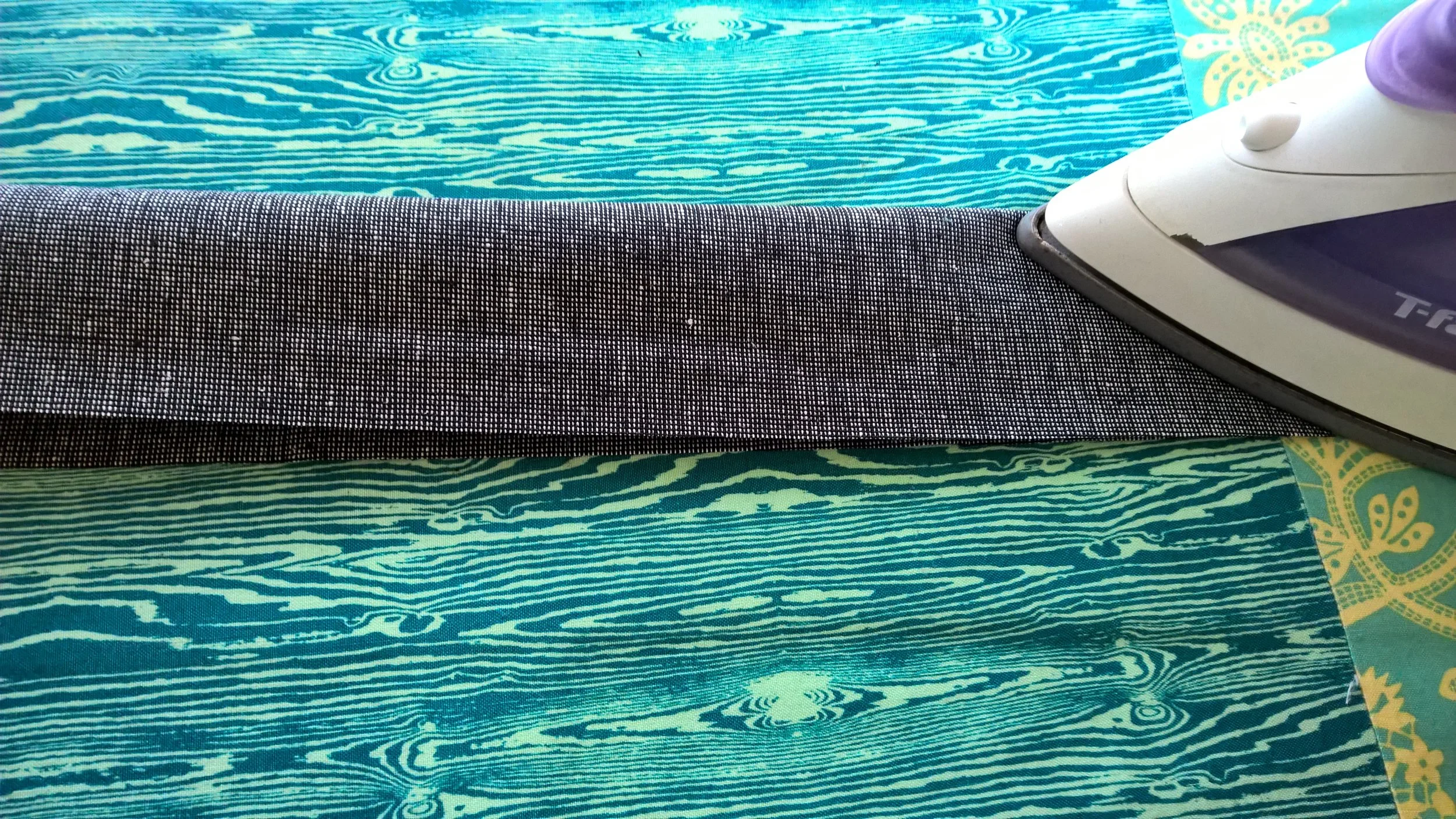 Pressing a center crease after folding fabric in half lengthwise.