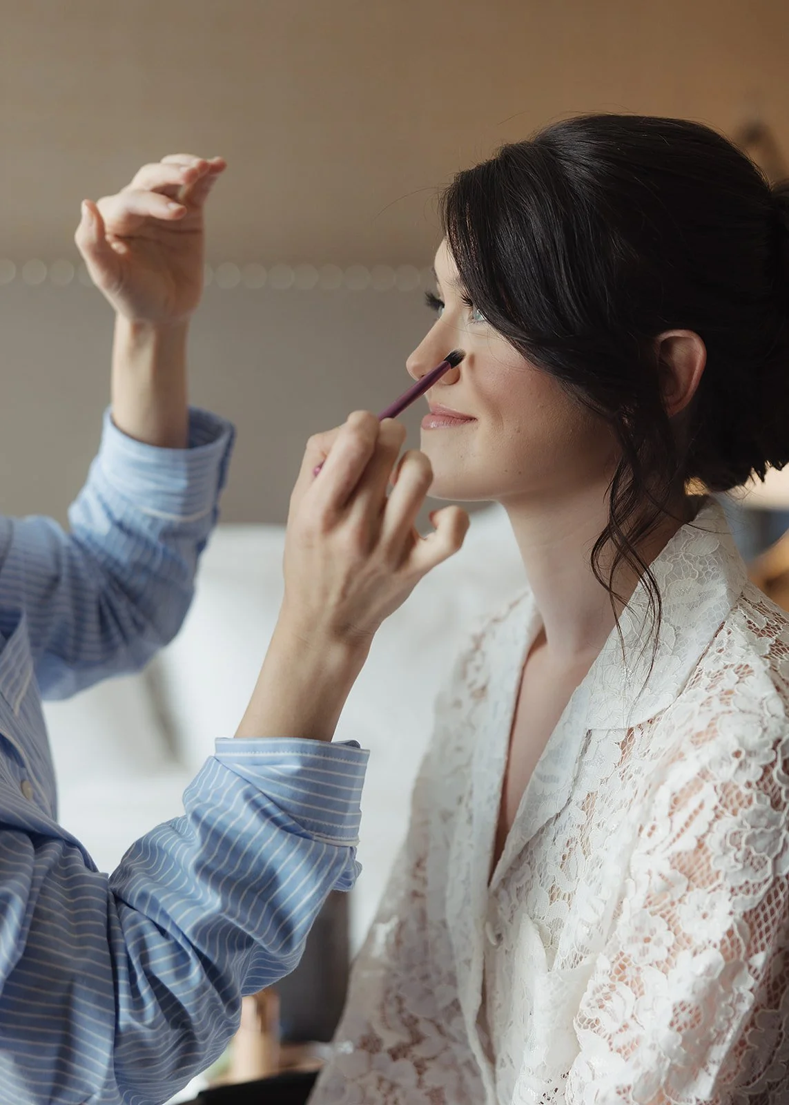 A woman getting her makeup done, with a makeup artist applying eyeshadow.
