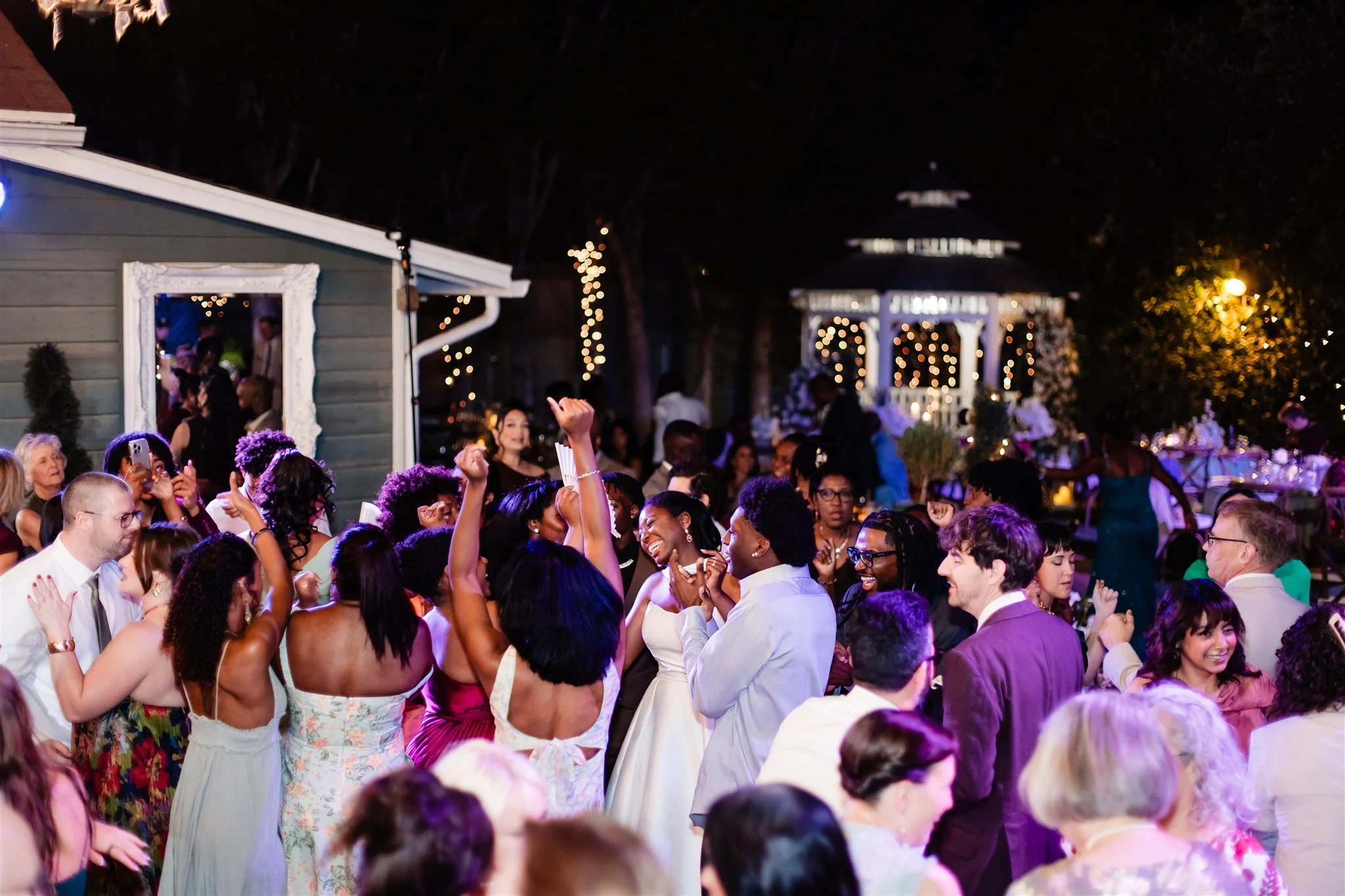 Bride smiling and dancing at the center of a full dance floor surrounded by guests at the end of the night