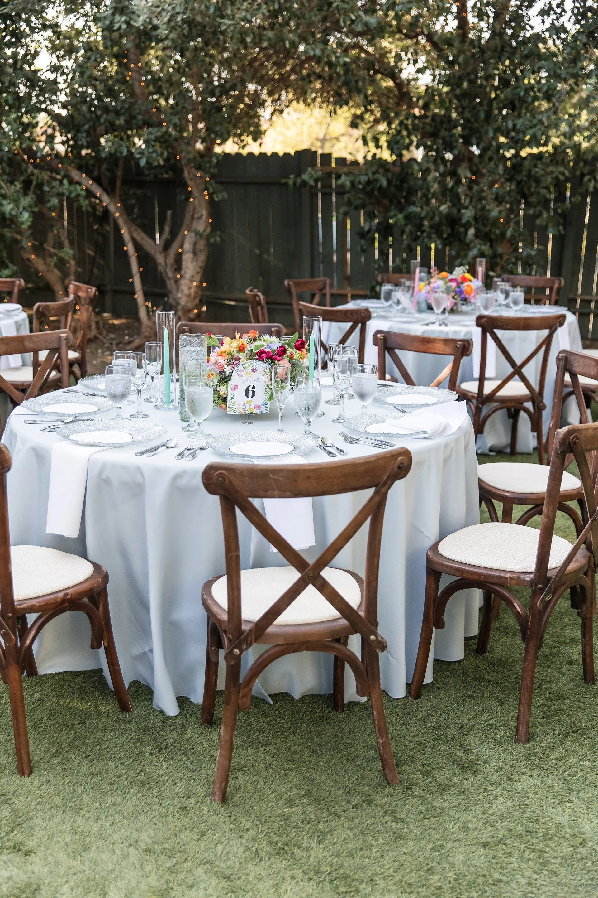 Close-up of a wedding reception table set with rustic cross back chairs at The Christmas House