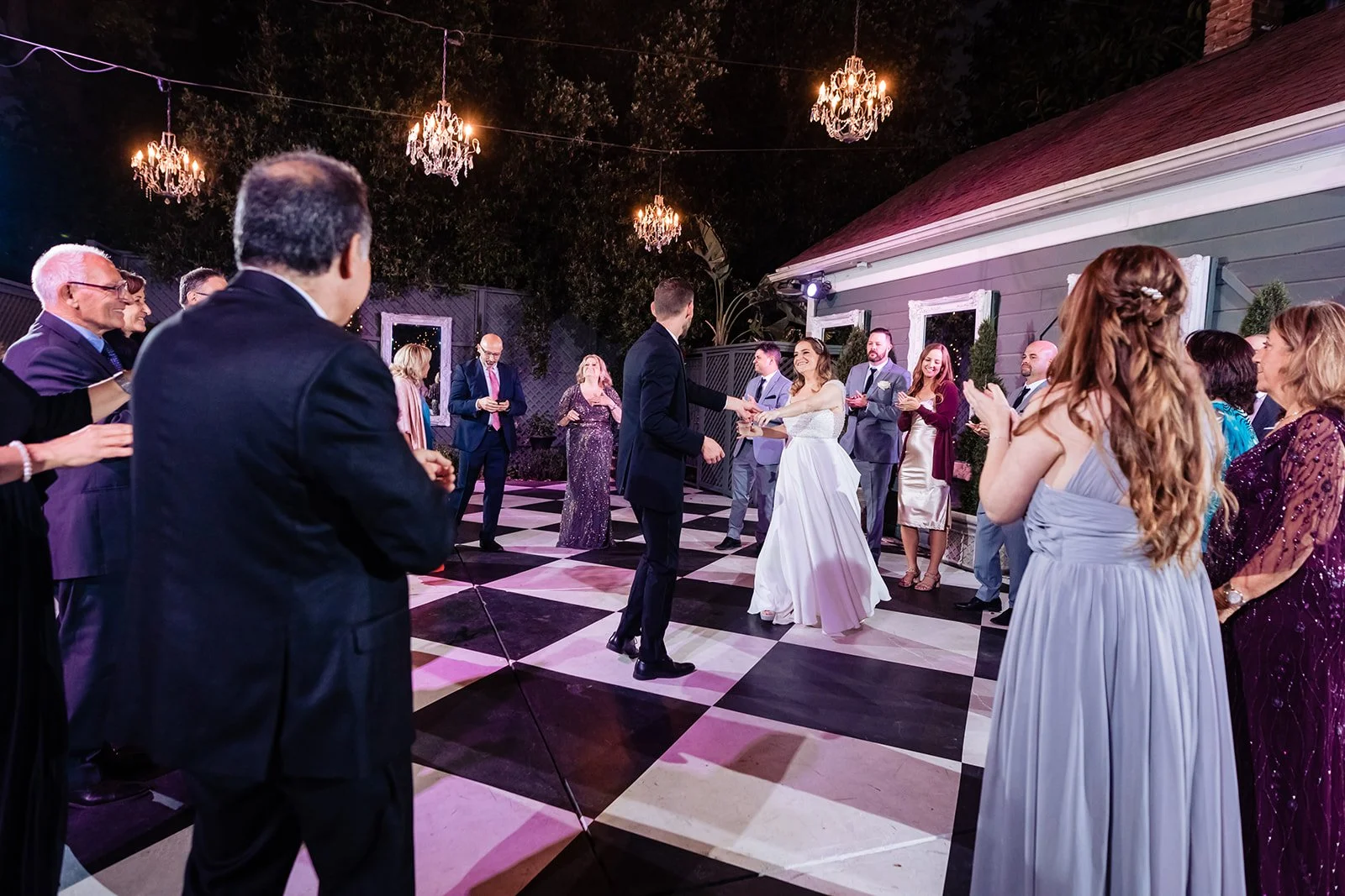 couple having their last dance surrounded by family and friends on a black and white checkered dance floor at the Christmas House