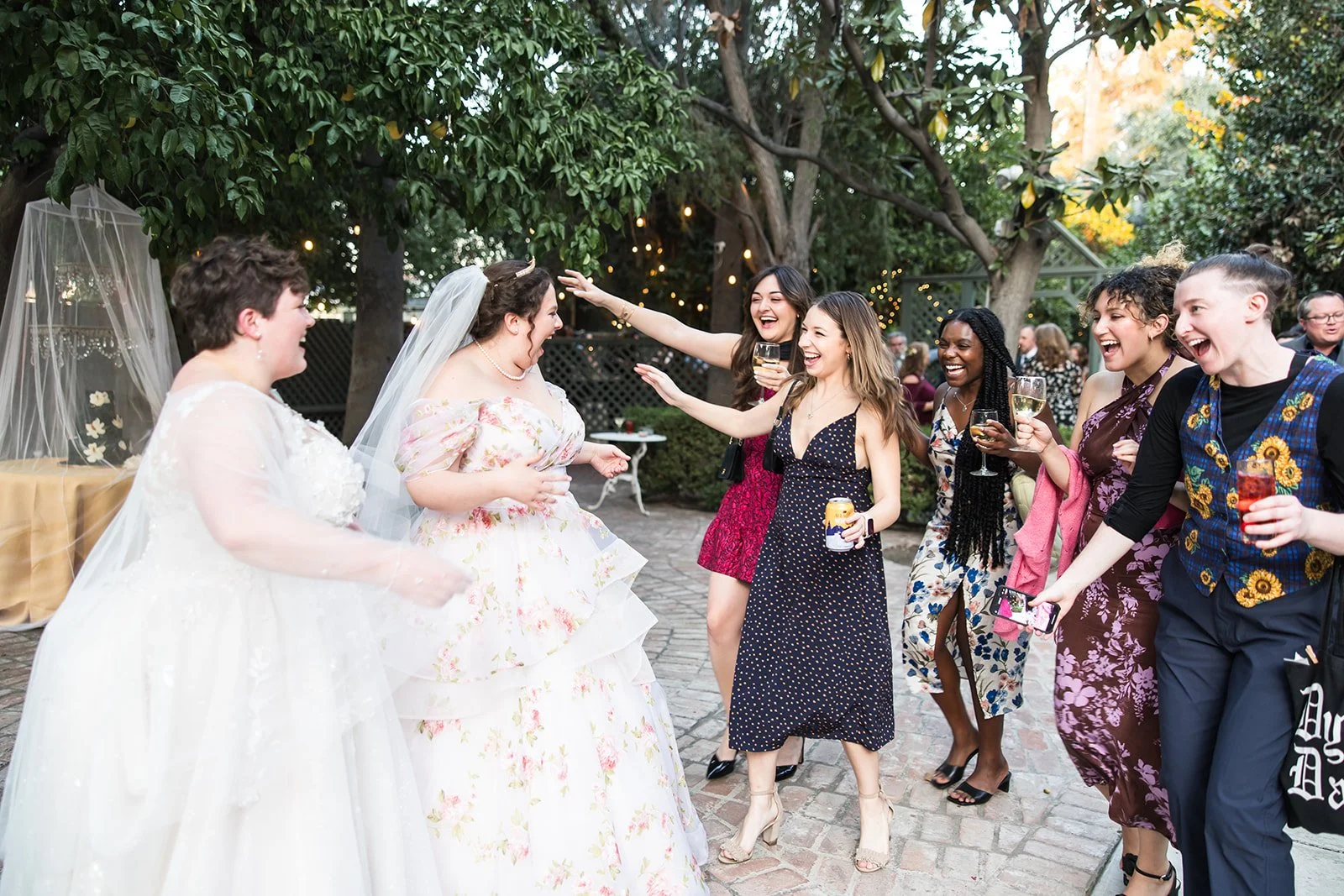 same sex couple welcoming happy guests at their garden wedding reception