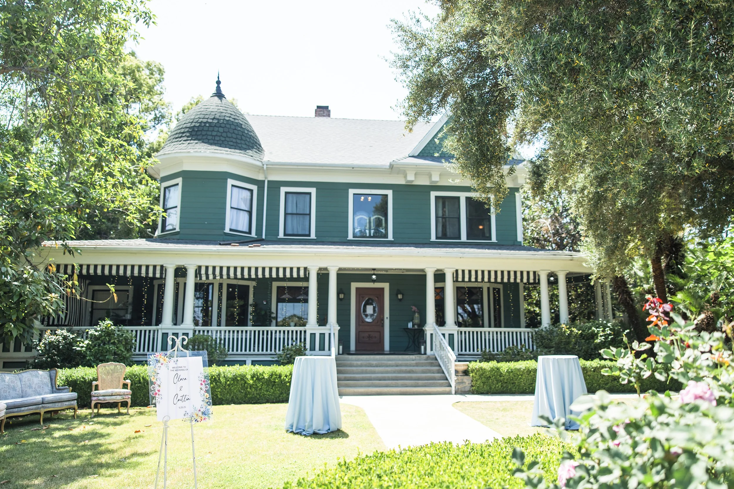 Front lawn wedding setup at The Christmas House with welcome sign, lounge seating, and cocktail tables
