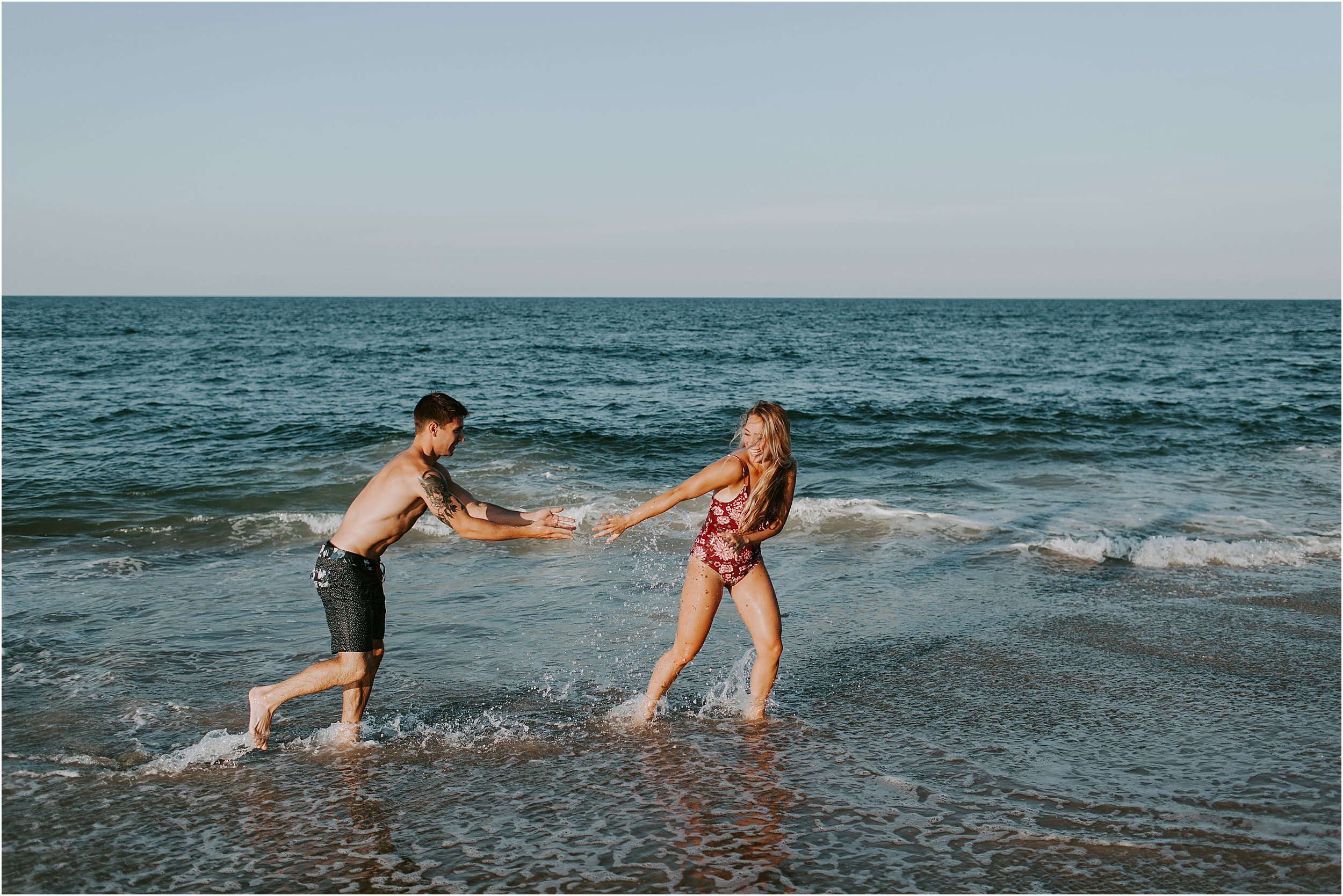  A couple in bathing suits plays in the water at the beach. 