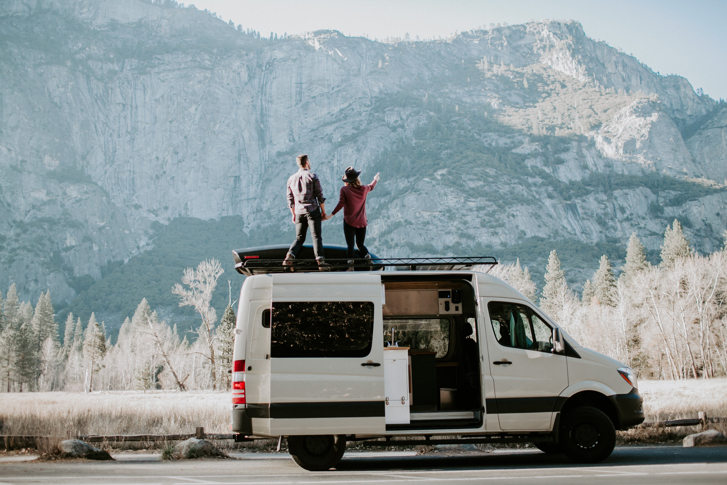 A couple stands on top of their white sprinter van, taking in the view of Yosemite Valley. 