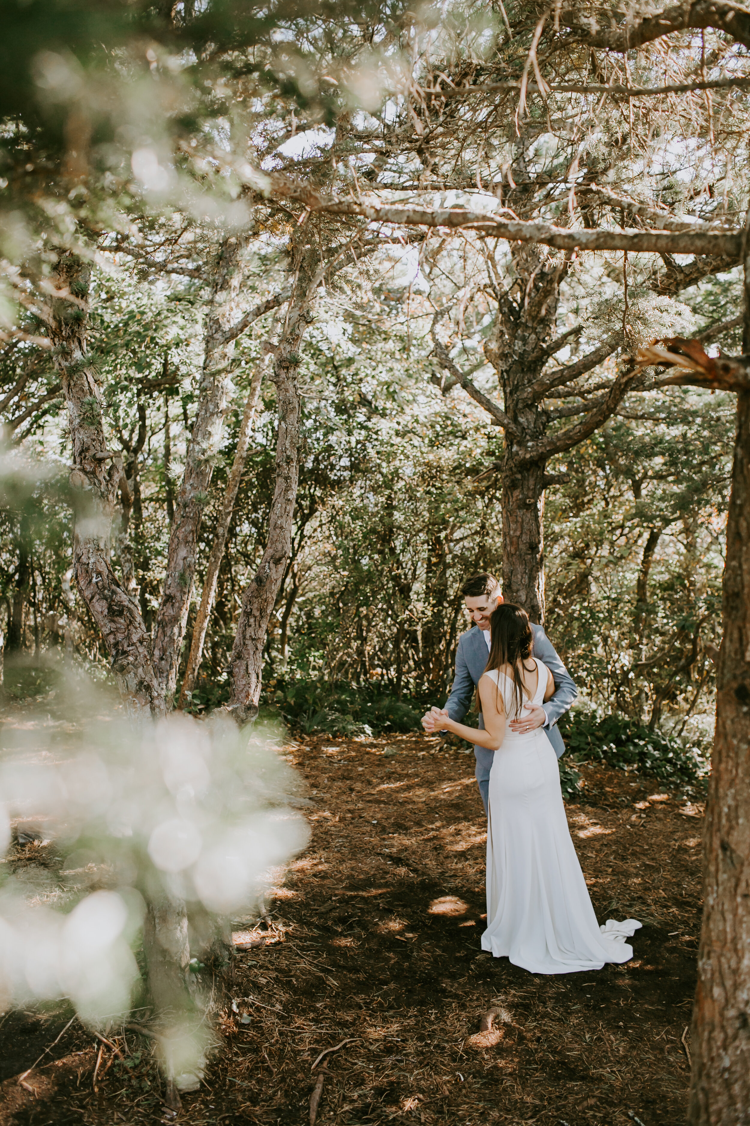 A bride and groom dancing in the woods.