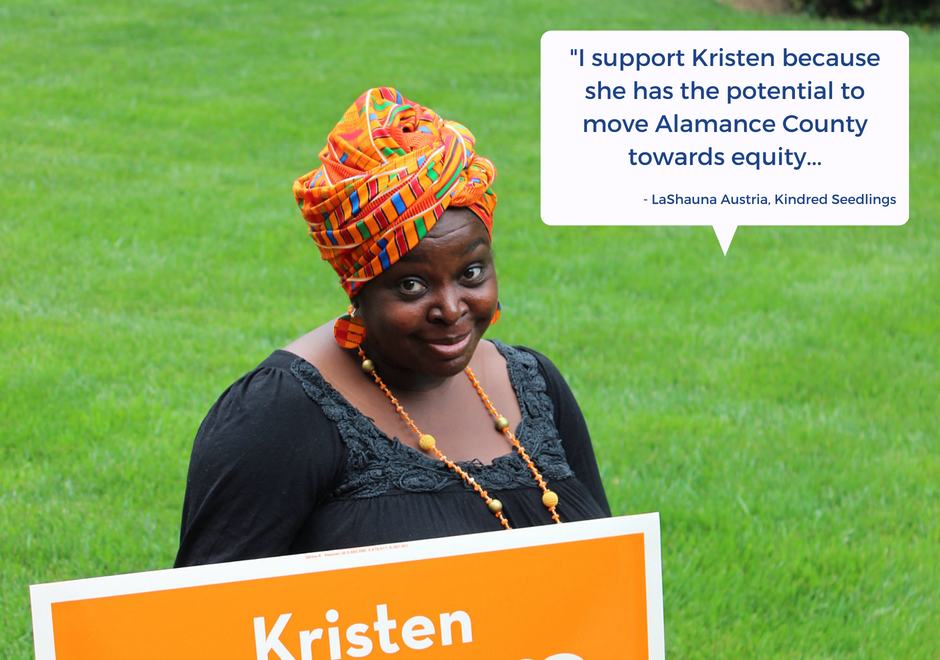 Caption: LaShauna Austria stands holding a Kristen Powers yard sign.