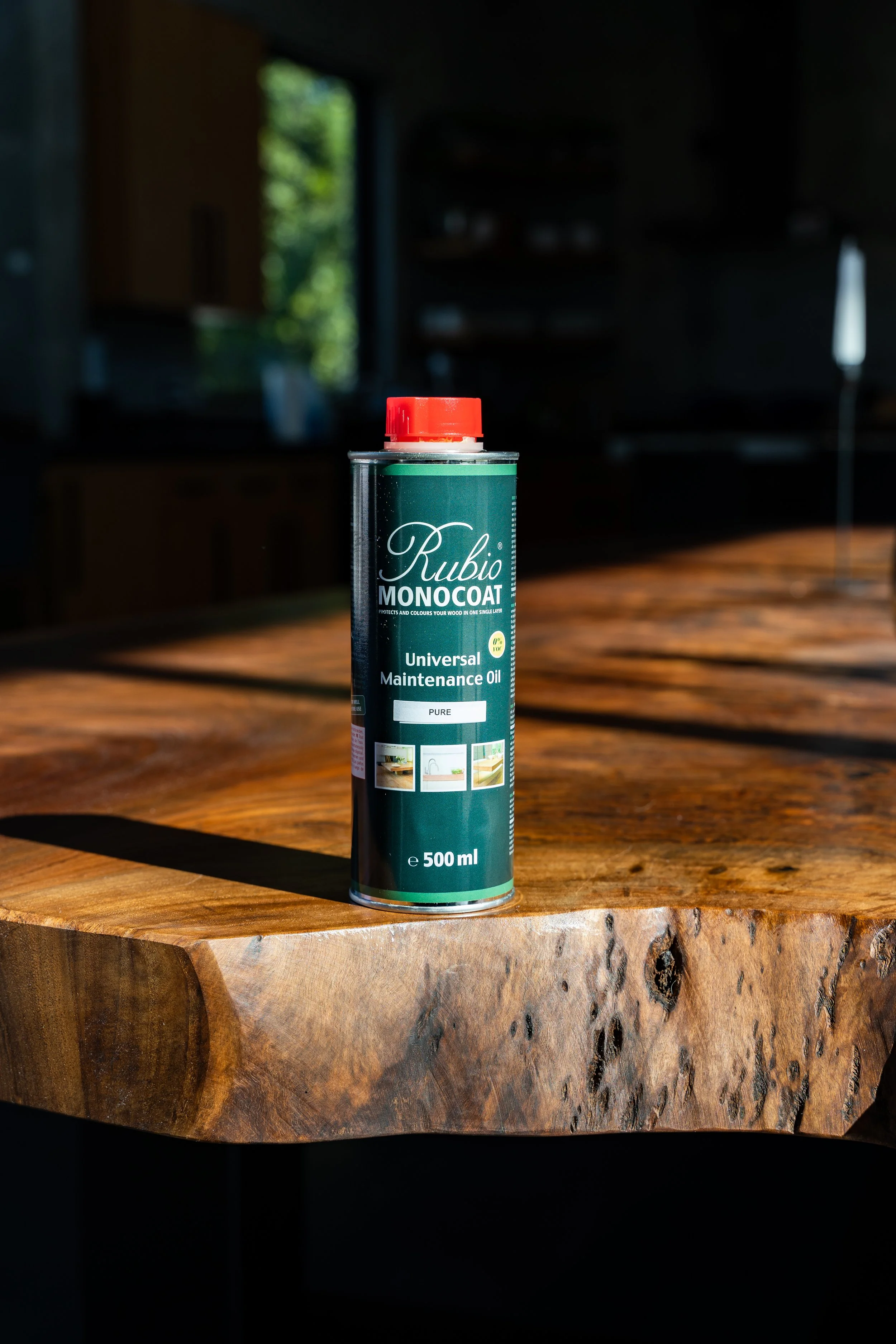 Rubio Monocoat Universal Maintenance Oil bottle on live edge wooden table, premium hardwax oil used for nourishing and maintaining custom live edge dining tables by Kristopher Kirkpatrick