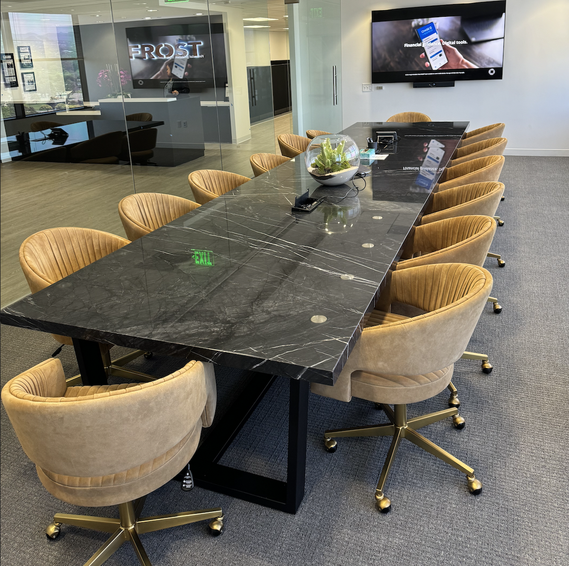 Large black quartzite stone conference table with power grommets in a modern executive boardroom, surrounded by tan velvet swivel chairs, custom handcrafted by Kristopher Kirkpatrick in San Diego
