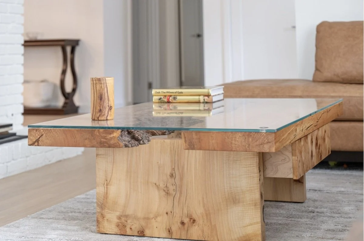 Live edge burled maple river table coffee table featuring custom glass river and wooden trestle base
