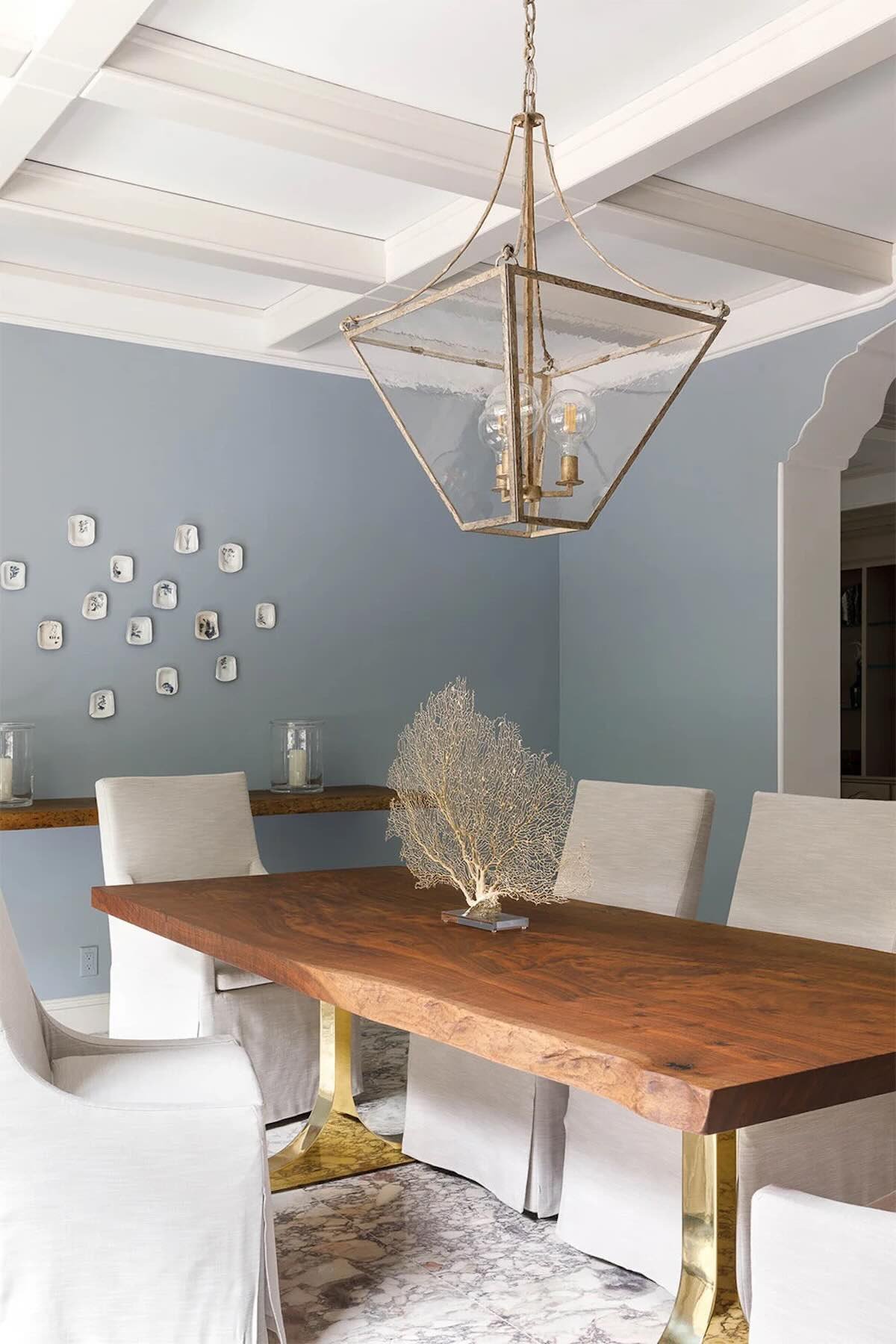 Custom live edge walnut dining table featuring dramatic natural grain and sculptural brass wishbone base