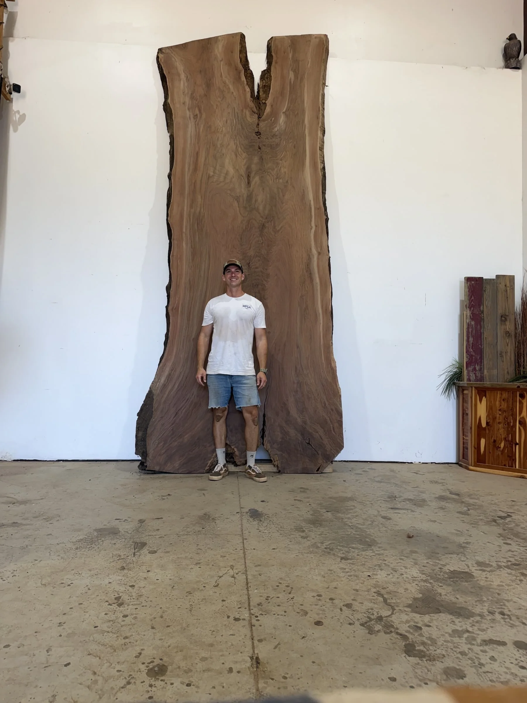 Kristopher Kirkpatrick standing beside an extra-large live edge walnut slab for a custom table