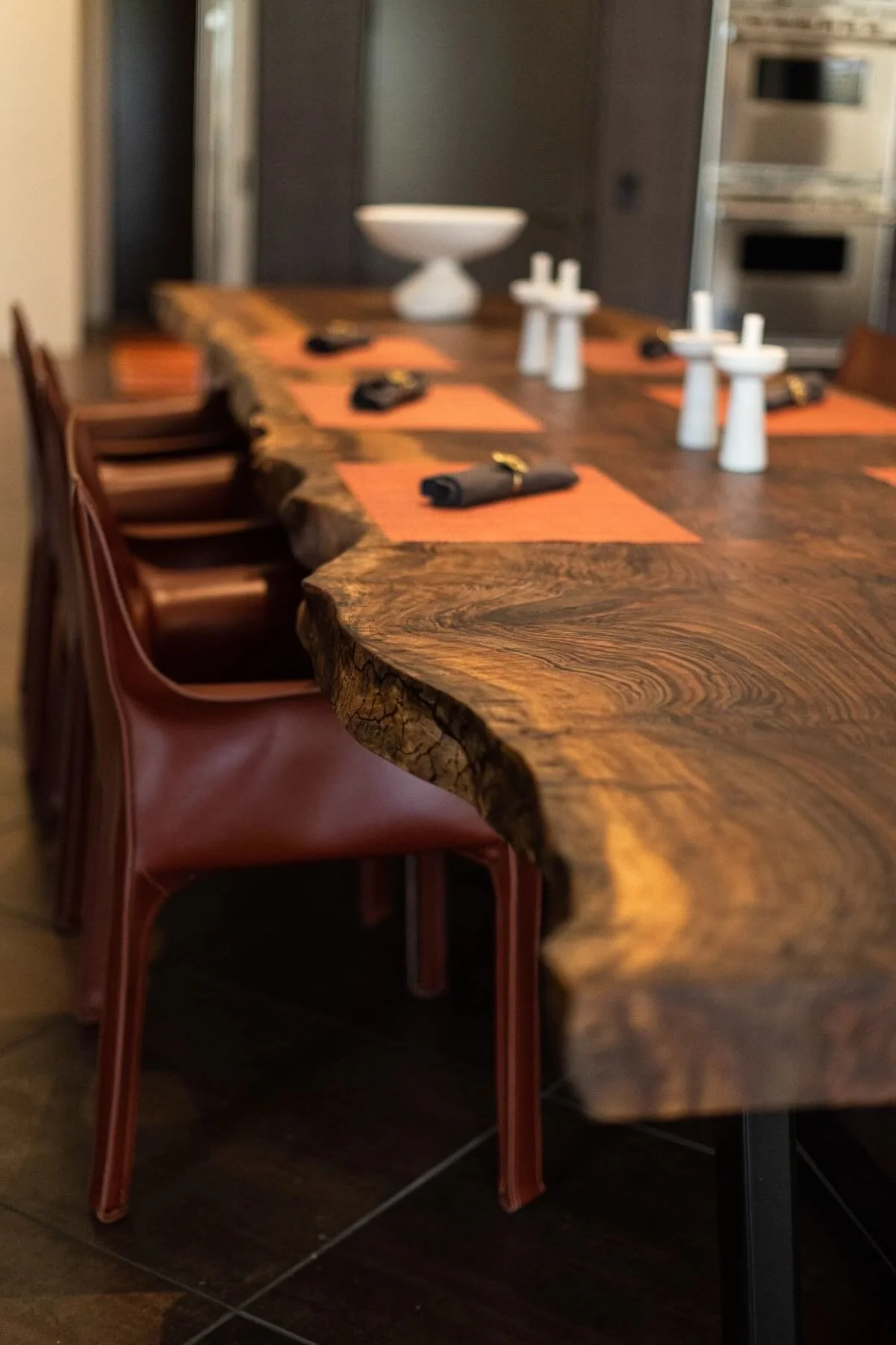 Close-up of rich Bastogne walnut live edge dining table top with natural grain and set for dining