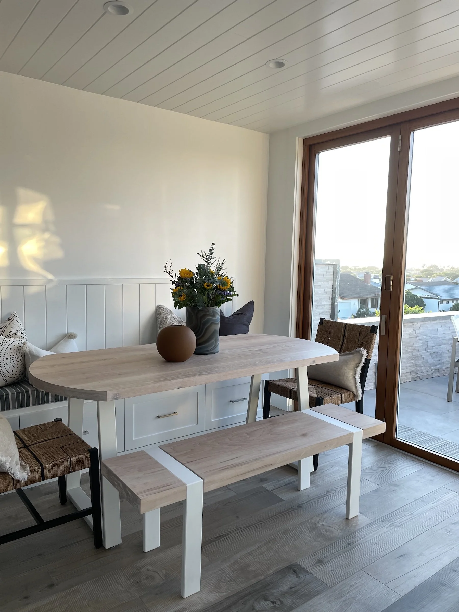 Custom oval white oak dining table with white trapezoid base and matching bench