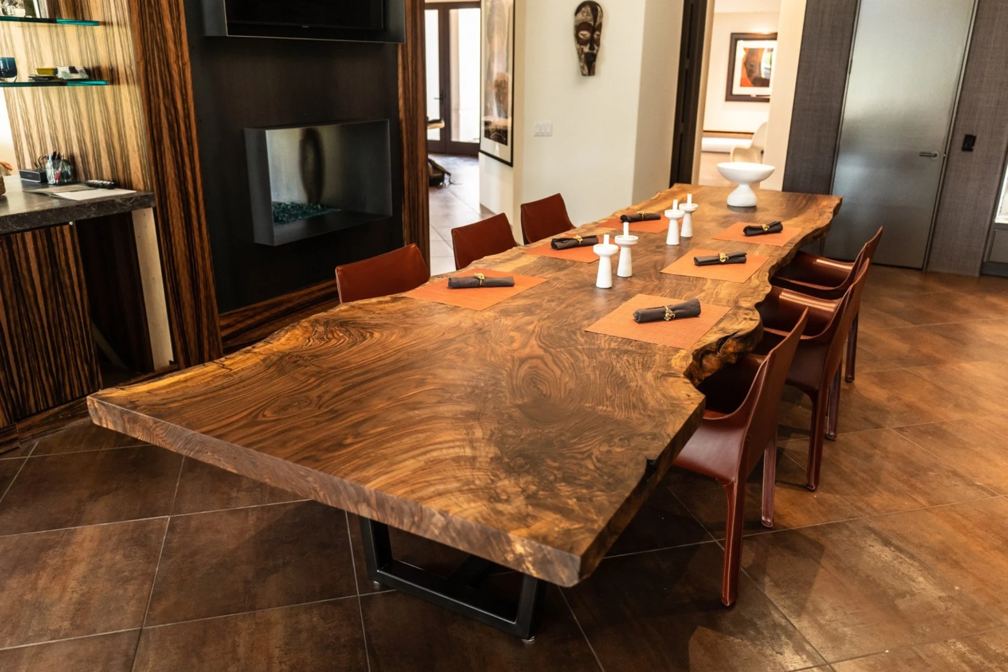 20-foot Bastogne walnut dining table with a richly figured live-edge top, 4–5 feet wide, and a black metal base.