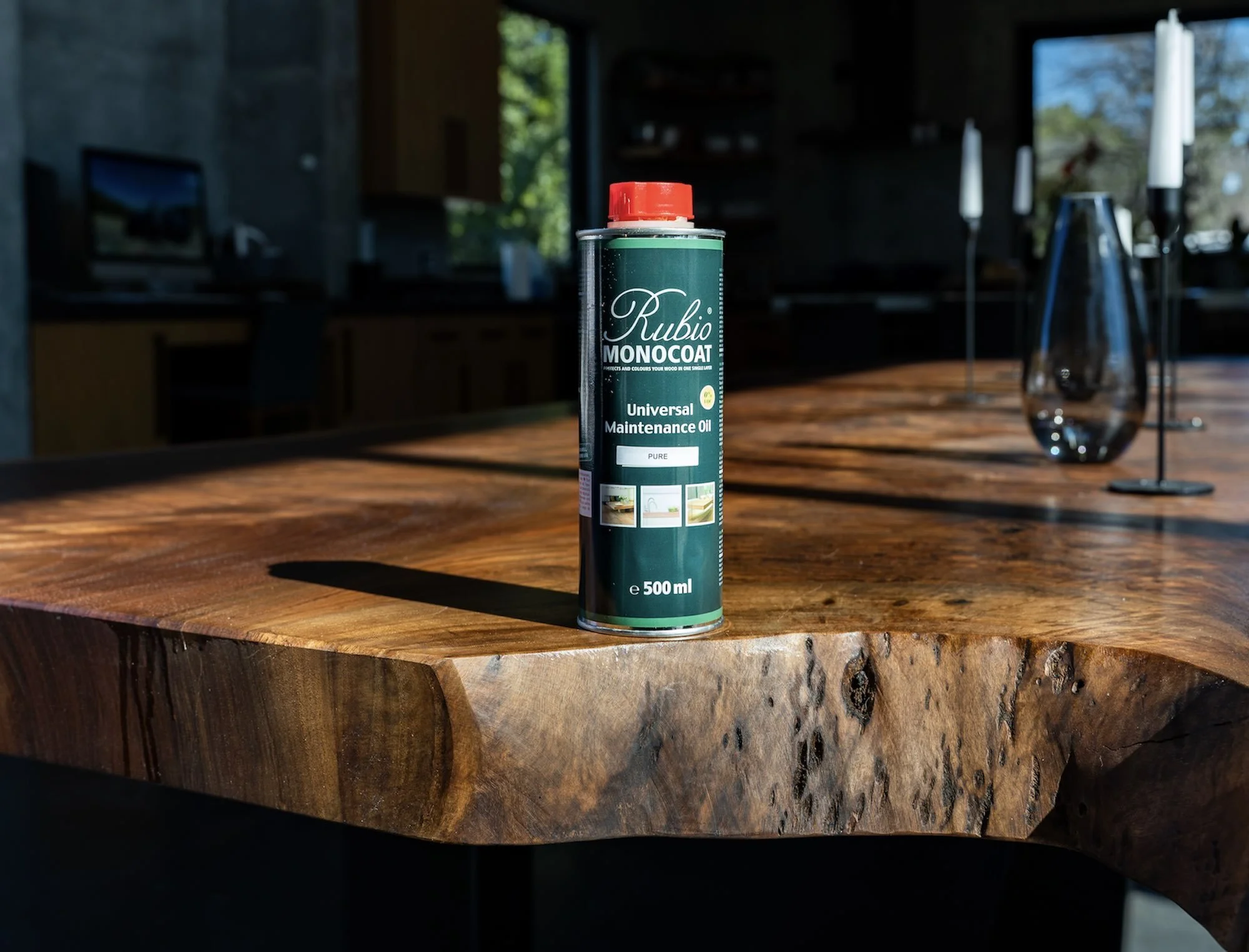 Rubio Monocoat Universal Maintenance Oil bottle standing on custom live edge Claro Walnut dining table, showing how the hardwax oil nourishes and protects the rich natural grain and live edges
