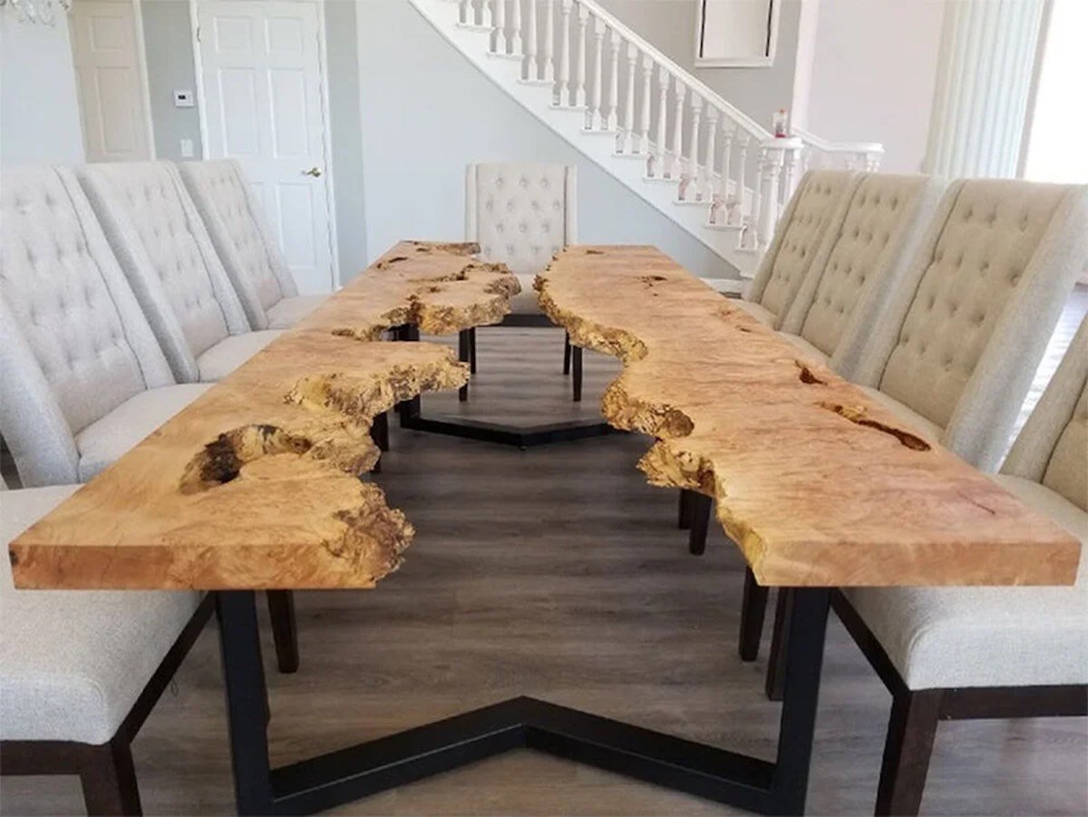 Live edge river table dining table featuring dramatic burled maple grain and black steel base in a modern home with staircase
