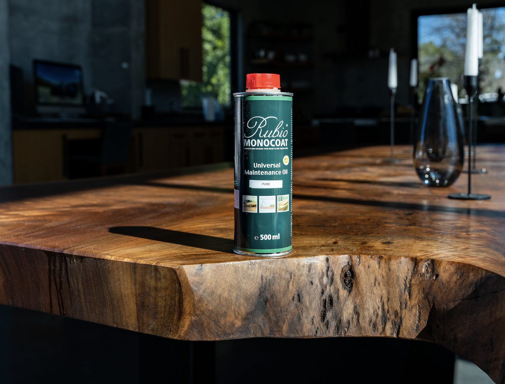 Rubio Monocoat Universal Maintenance Oil bottle standing on custom live edge Claro Walnut dining table, showing how the hardwax oil nourishes and protects the rich natural grain and live edges