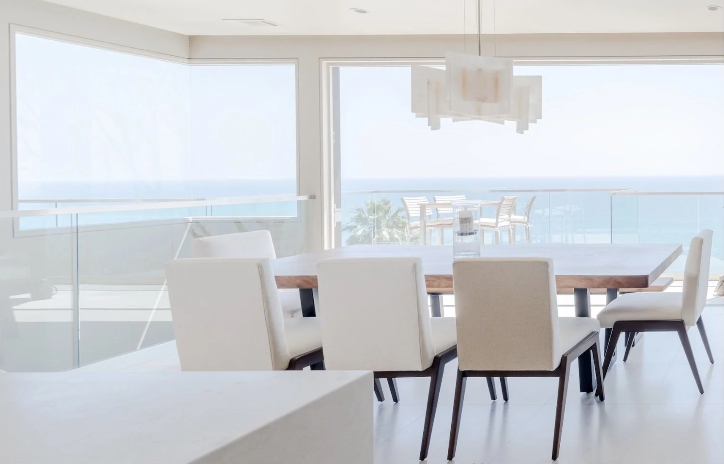 Custom handcrafted live edge walnut dining table finished with Rubio Monocoat hardwax oil in a bright, modern oceanfront home with floor-to-ceiling windows and panoramic Pacific Ocean views