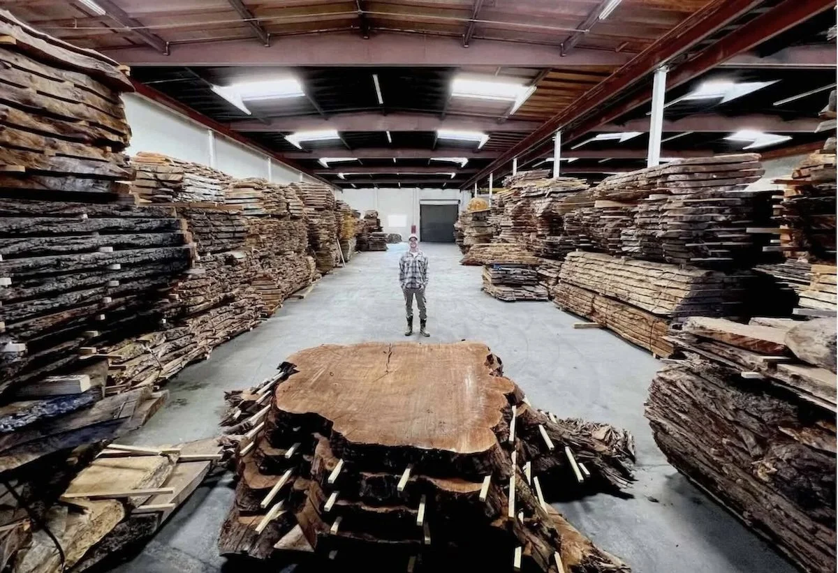 Kristopher Kirkpatrick standing in his San Diego workshop surrounded by thousands of premium live edge wood slabs