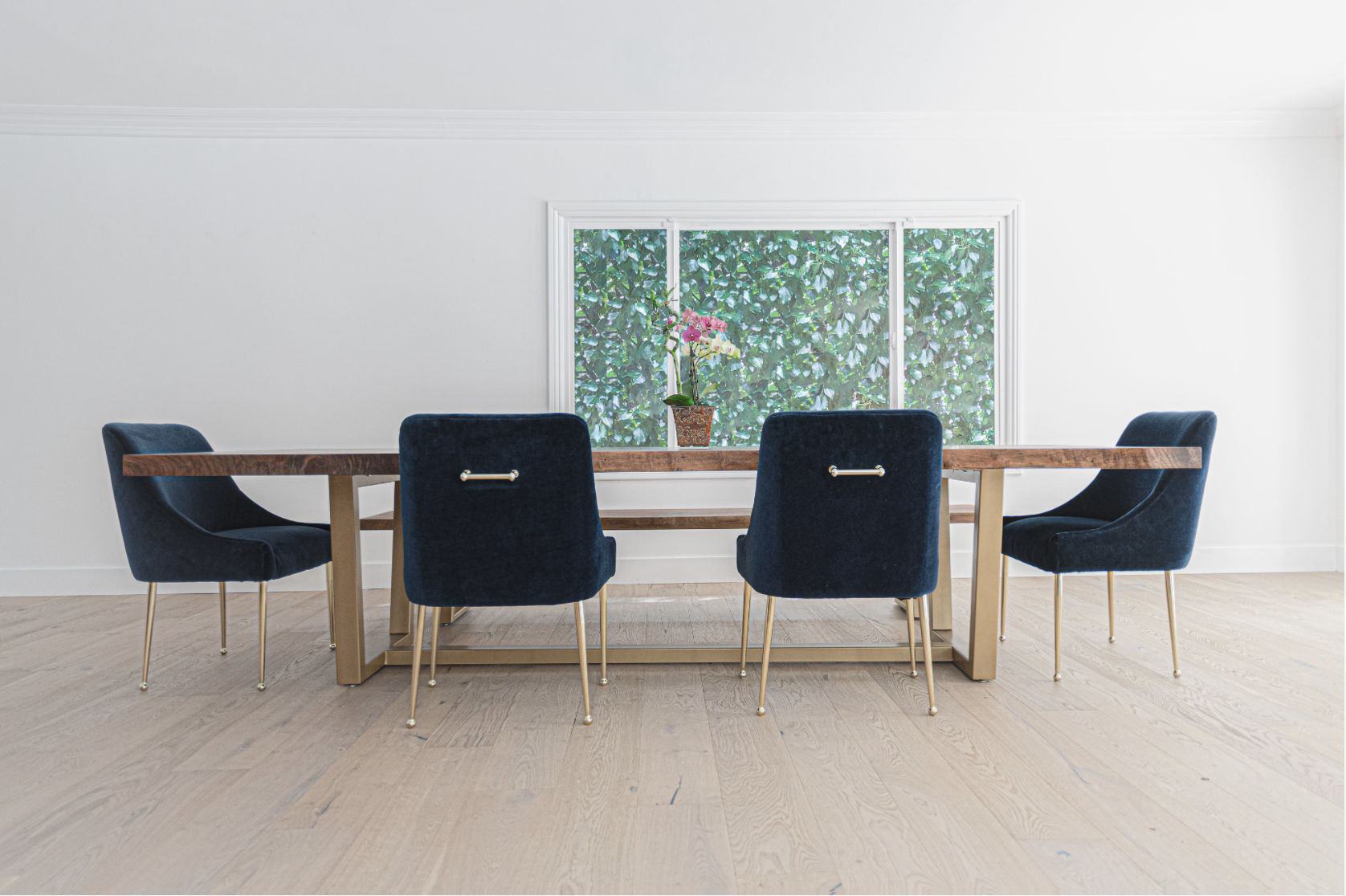 Custom 8-foot single slab Claro walnut live edge dining table with brushed gold steel base and matching walnut bench, handcrafted by Kristopher Kirkpatrick in San Diego, California.