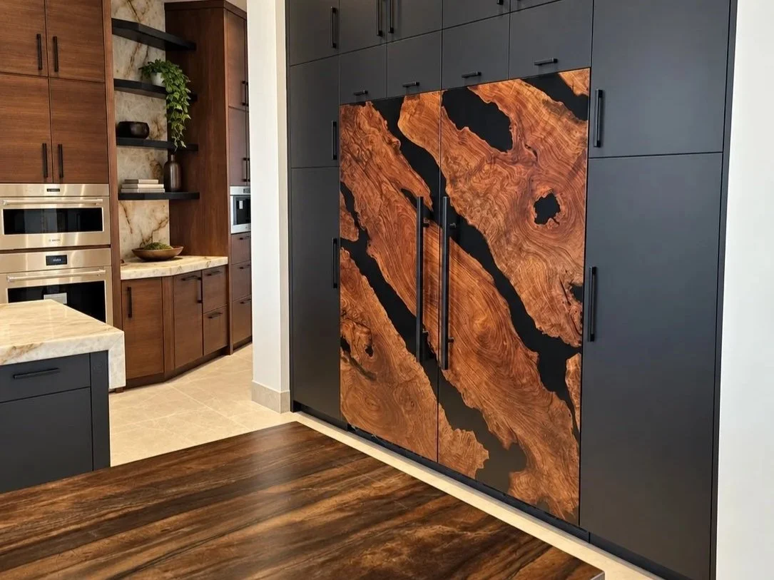 Custom Sub-Zero refrigerator panels featuring richly figured Claro walnut and contrasting black epoxy resin, installed in a luxury kitchen with dark cabinetry.