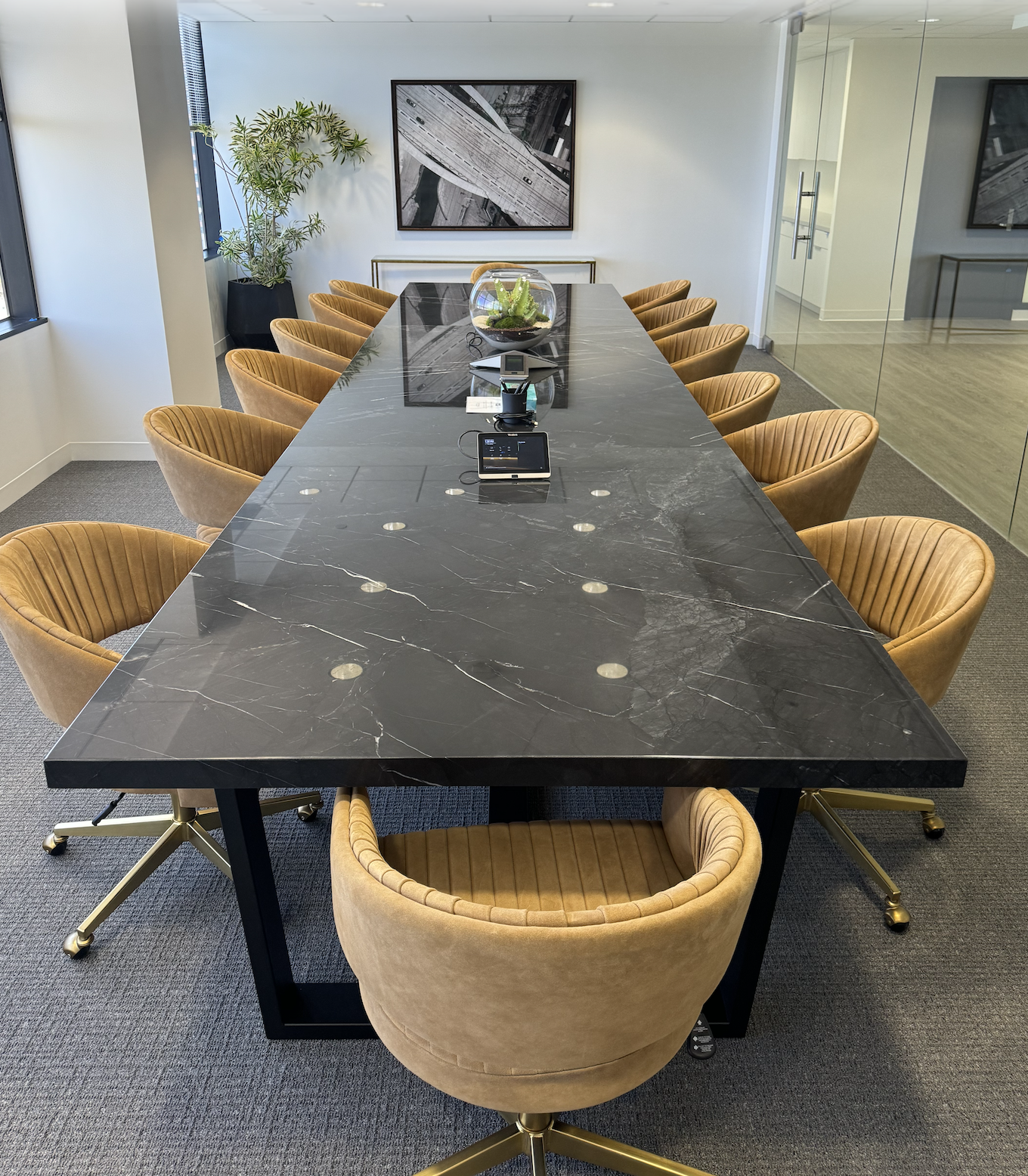 Long black quartzite stone conference table with power grommets and gold base in a modern professional office, surrounded by tan velvet swivel chairs, custom handcrafted by Kristopher Kirkpatrick in San Diego