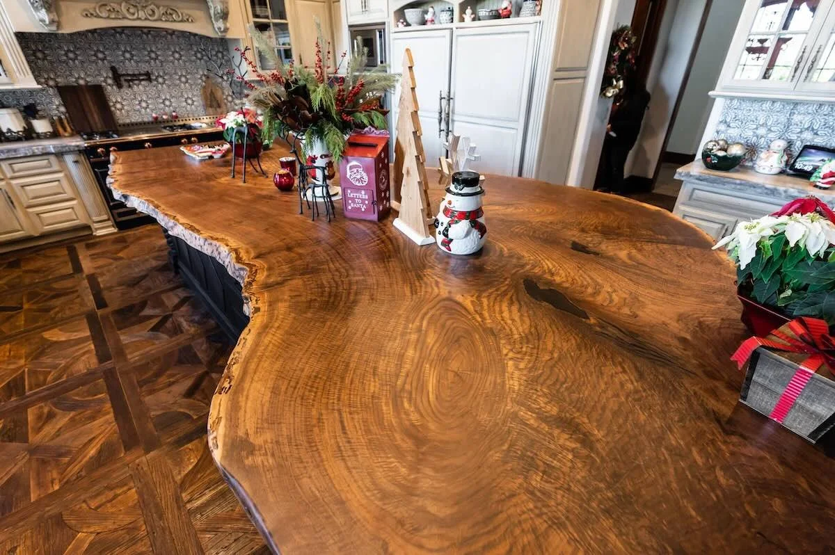 Side view of massive live edge walnut kitchen island showing thick slab profile and twisted black base