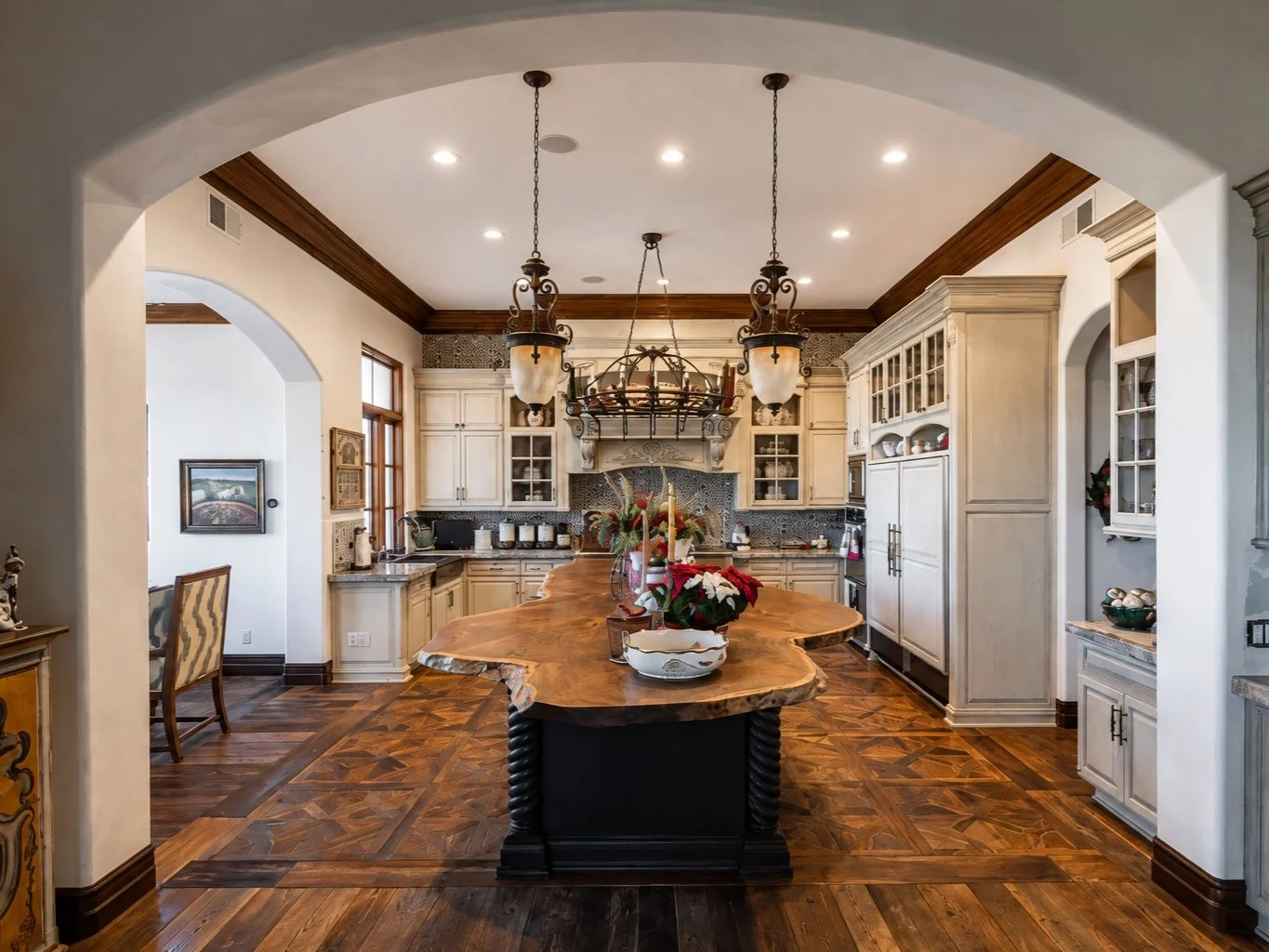 Custom live-edge Claro walnut kitchen island with a sculptural natural edge and dark pedestal base in a luxury custom kitchen.
