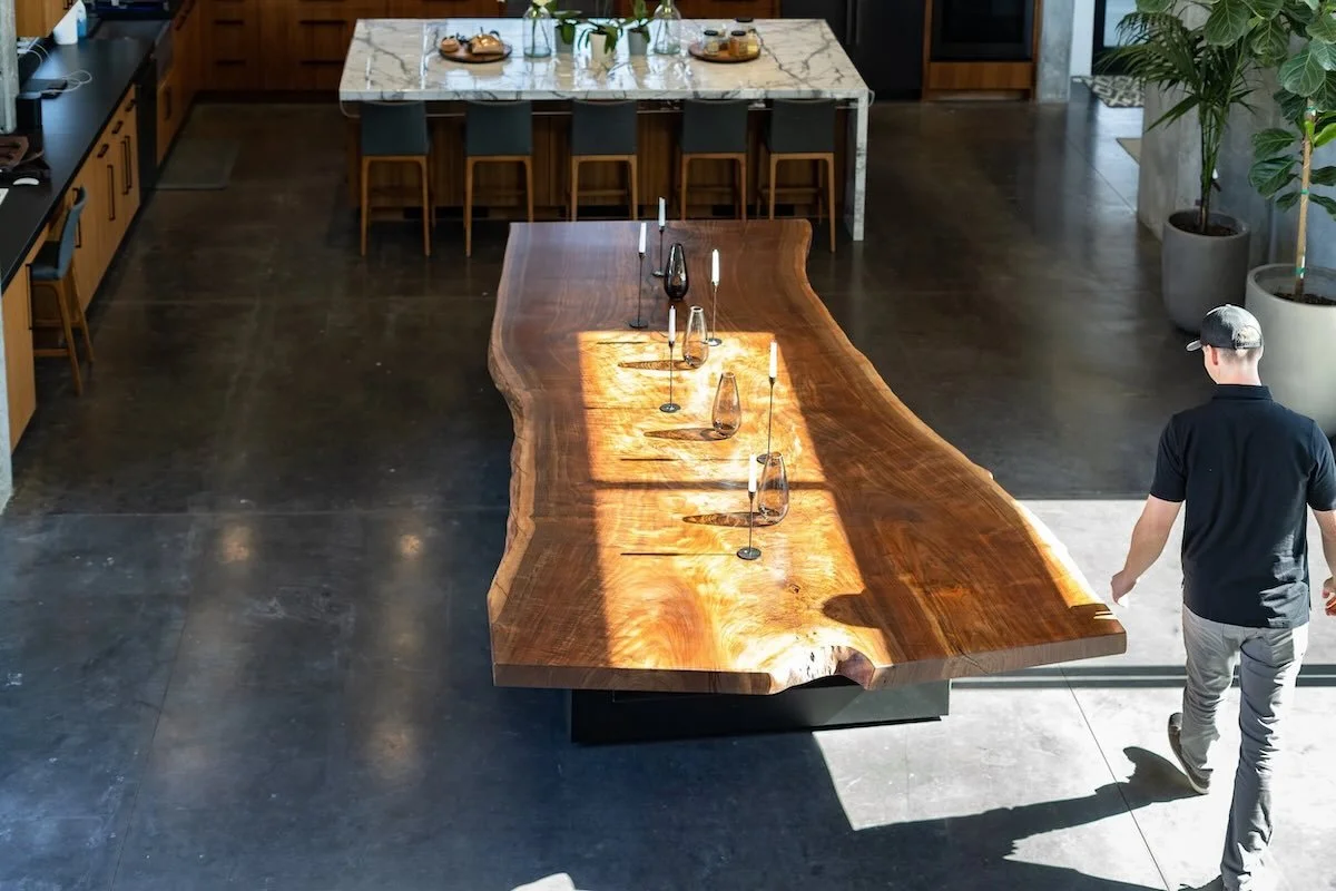 Long historic live edge Claro walnut dining table set for dinner with dramatic grain and live edges in a contemporary dining area