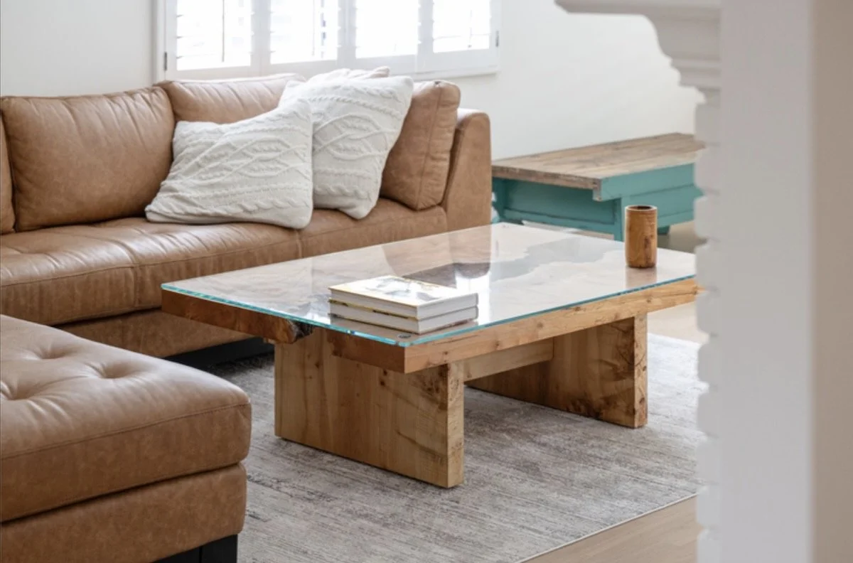 Burled maple river table coffee table with glass insert shown in a bright living room setting
