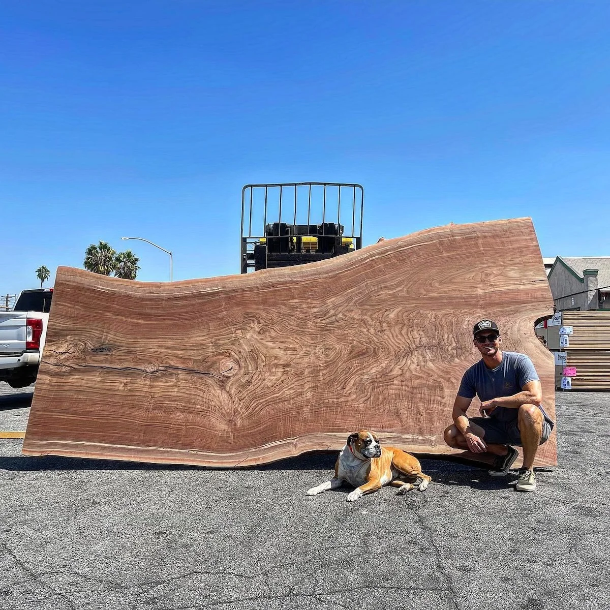 Kristopher Kirkpatrick with his dog beside an oversized raw Claro walnut slab used to build a custom live edge dining table for a Los Angeles home