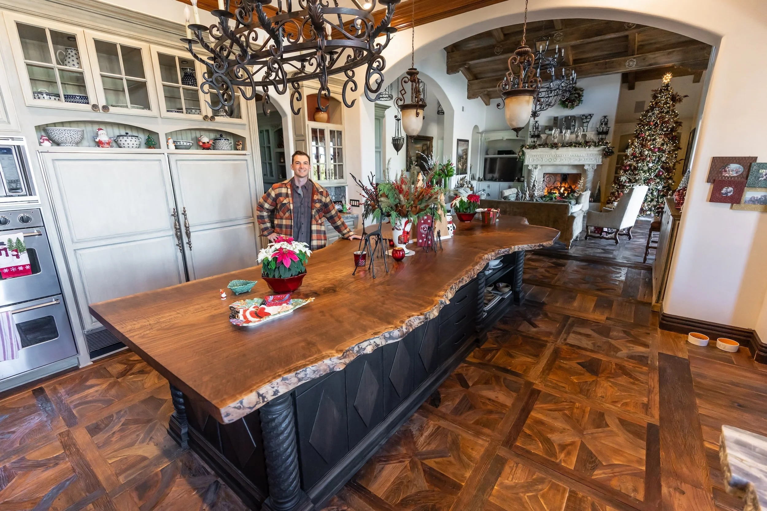 Custom single-slab live edge Claro walnut kitchen island handcrafted and installed by Kristopher Kirkpatrick in a luxury home, featuring natural wood grain and a dark custom base.