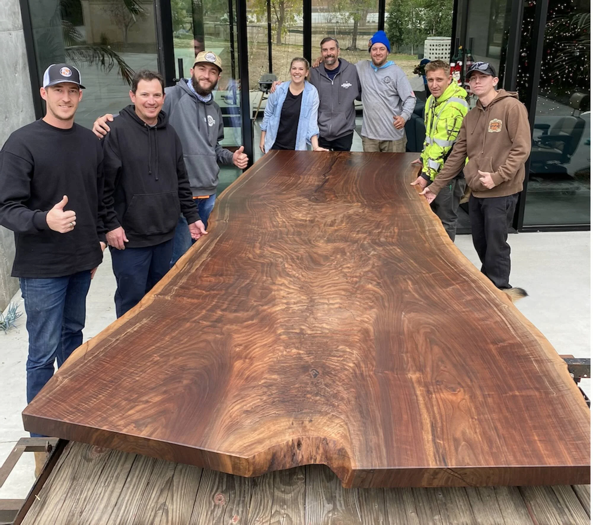 Kristopher Kirkpatrick and his team with a happy client family proudly standing behind their newly delivered and installed custom live edge walnut dining table in San Diego