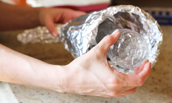 Now remove the water bottle and stretch out the center so you have a wide opening. If you feel your mold still isn't strong enough you can stuff the center with foil. DO NOT leave the water bottle inside the mold. Also, now is the time to bend the end of the "tail" - Traditional cornucopias curve at the end. Just use your hands to mold the foil. Now set aside and grab your dough.