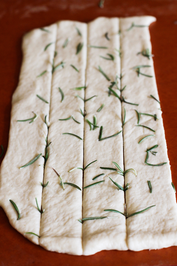 This is my rosemary version. If you want to add herbs to your dough sprinkle the herbs on and then go ahead and roll the dough with your rolling pin every so slightly so they all press into the dough. They still tend to pop up a bit, but it wont matter once you cook it.