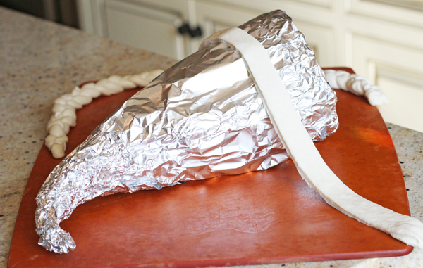 Now here is where you can get creative! Start by spraying your foil with non-stick cooking spray. All around the foil - especially near the tail portion because this is where it can get stuck once it's baked. Now for the dough. If you want a simple flat look (like my rosemary cornucopia) just layer your pieces one by one so they are slightly overlapping. This dough does not expand much so you want to make sure there are no gaps between the pieces. Start about 1 inch from the end so you can pull the foil out once it is baked. Also in this picture I will be adding a braided strip at the very front.