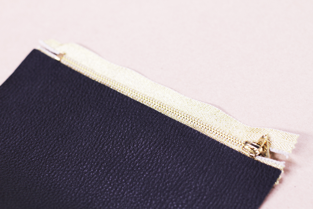 Now press your leather down to the glue. Run your finger across the leather so it firmly sticks to the zipper. If your zipper sticks out a tiny bit you can trim the edge.