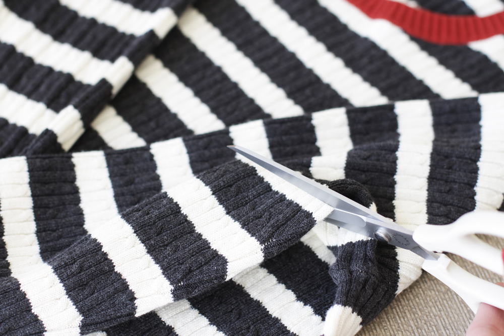 Using fabric scissors, cut the sleeves off of the sweater.