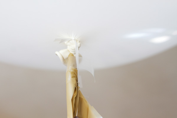 Using a piece of regular tape, wrap your first tassel around the balloon ribbon. 