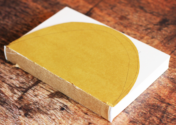 Your pages should all still be intact. Now using a pencil, draw a half circle as close to the edge of the pages as possible. My first line wasn't close enough so I drew another half circle. Cut along your half circle on your first page. This will be your guide for the rest of the pages. 