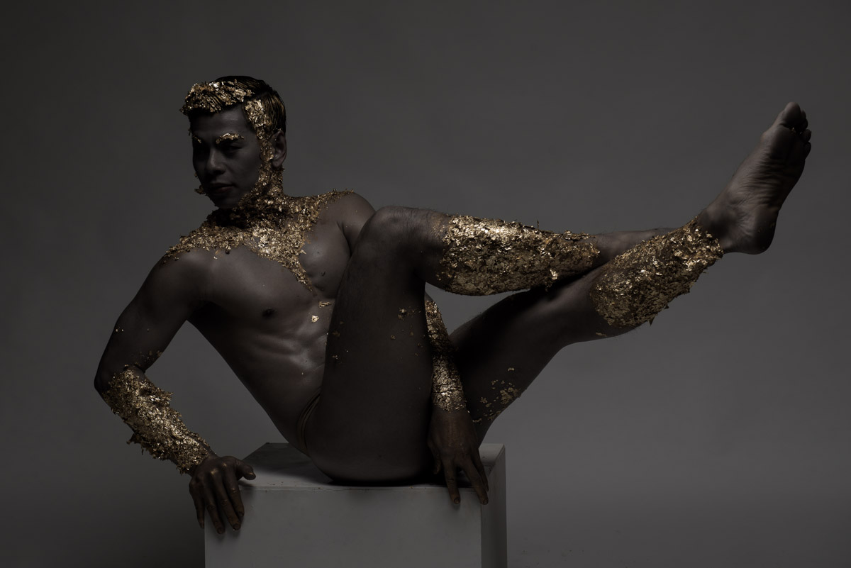 in gold paint a man. Shiny clavicle detail photo. Shiny body art