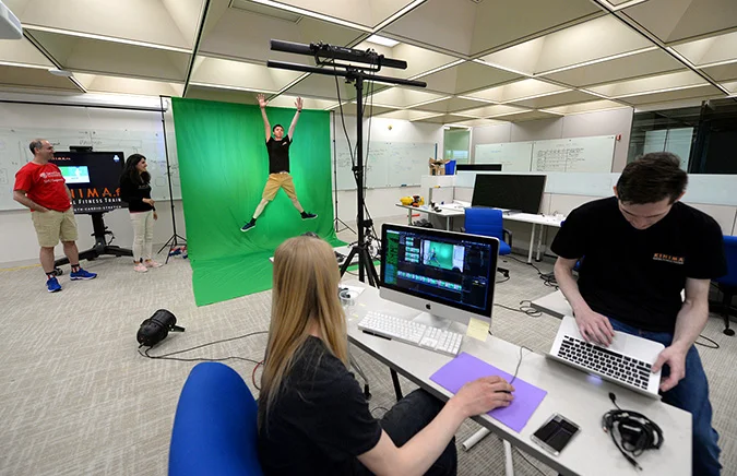 SHU Engineering Professor and Program Director Tolga Kaya and Kinima co-founder Renee Migdal look on as engineering students Gabe Bitencourt, Henry Sinclair and Nate Barone create workout videos as part of an internship in the maker space at West Campus.