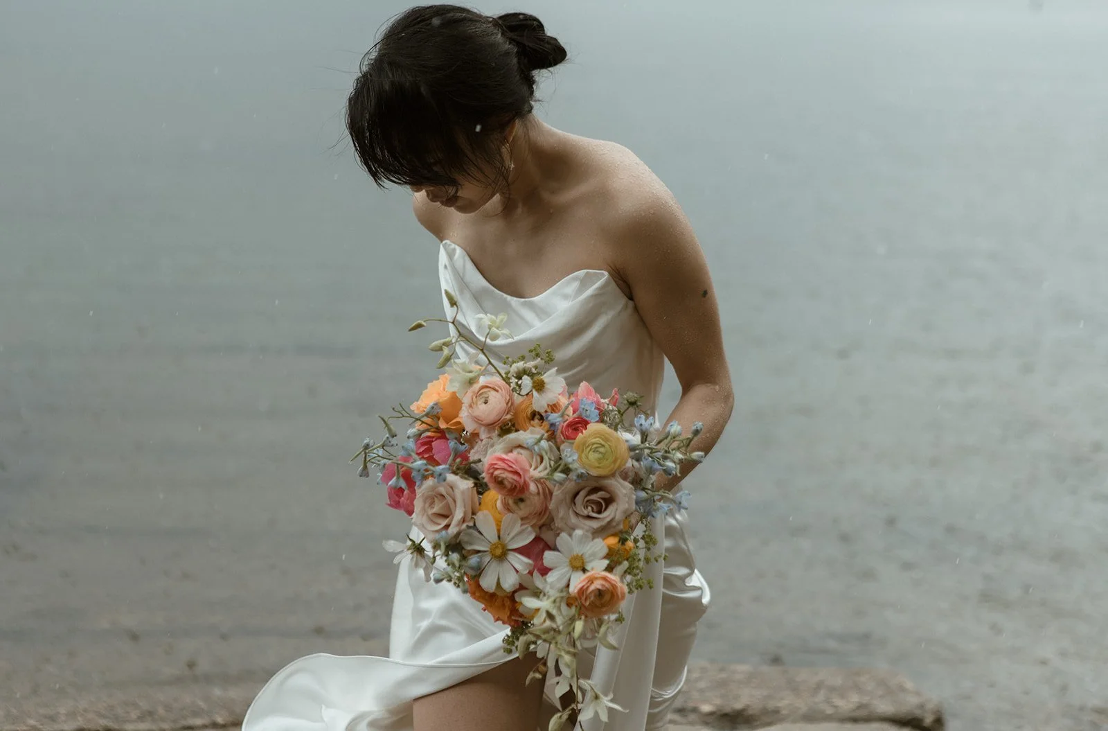Bride holds bouquet in the rain at Lake Wenatchee before their ceremony at Brown Family Homestead in Leavenworth.
