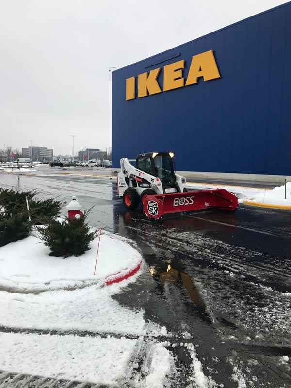 Bobcat with snow plow removing snow from Ikea parking lot, part of the landscaping services of Ivanoff Lawn Care and Landscaping.