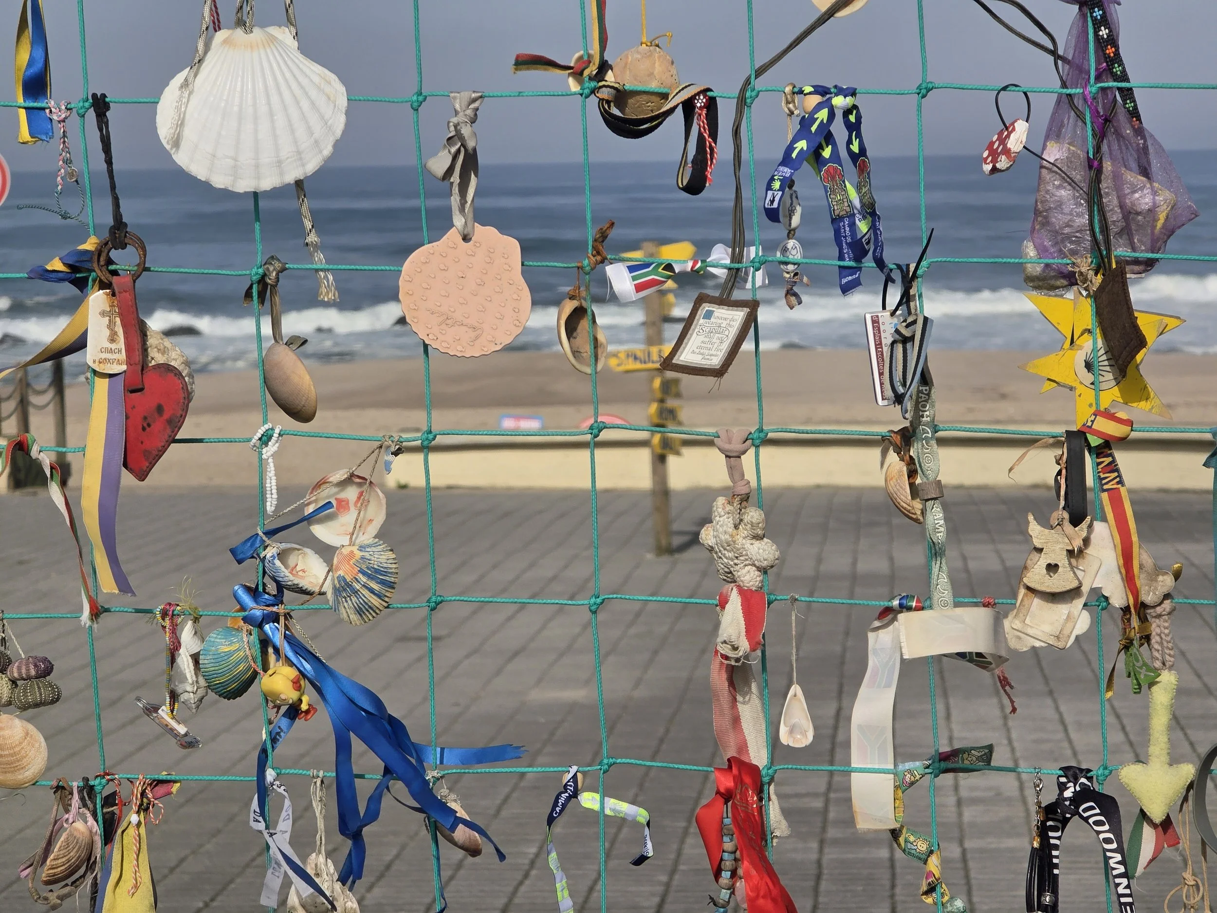 This is a "votive net" or memorial fencewhere pilgrims leave behind mementos, shells, and ribbons as symbols of their intentions, prayers, or the completion of a stage.
