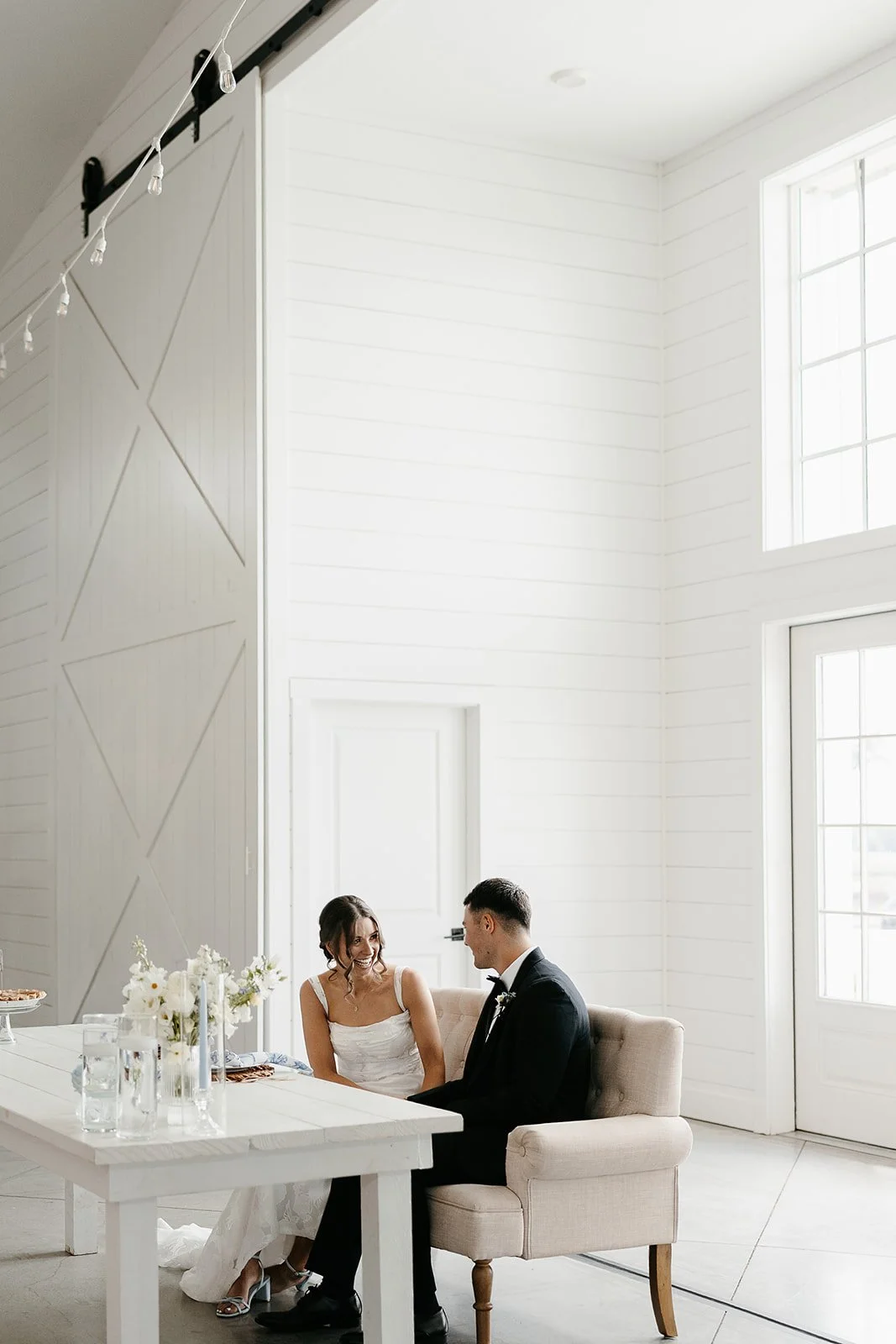 bride and groom in white barn wedding venue sharing private moment