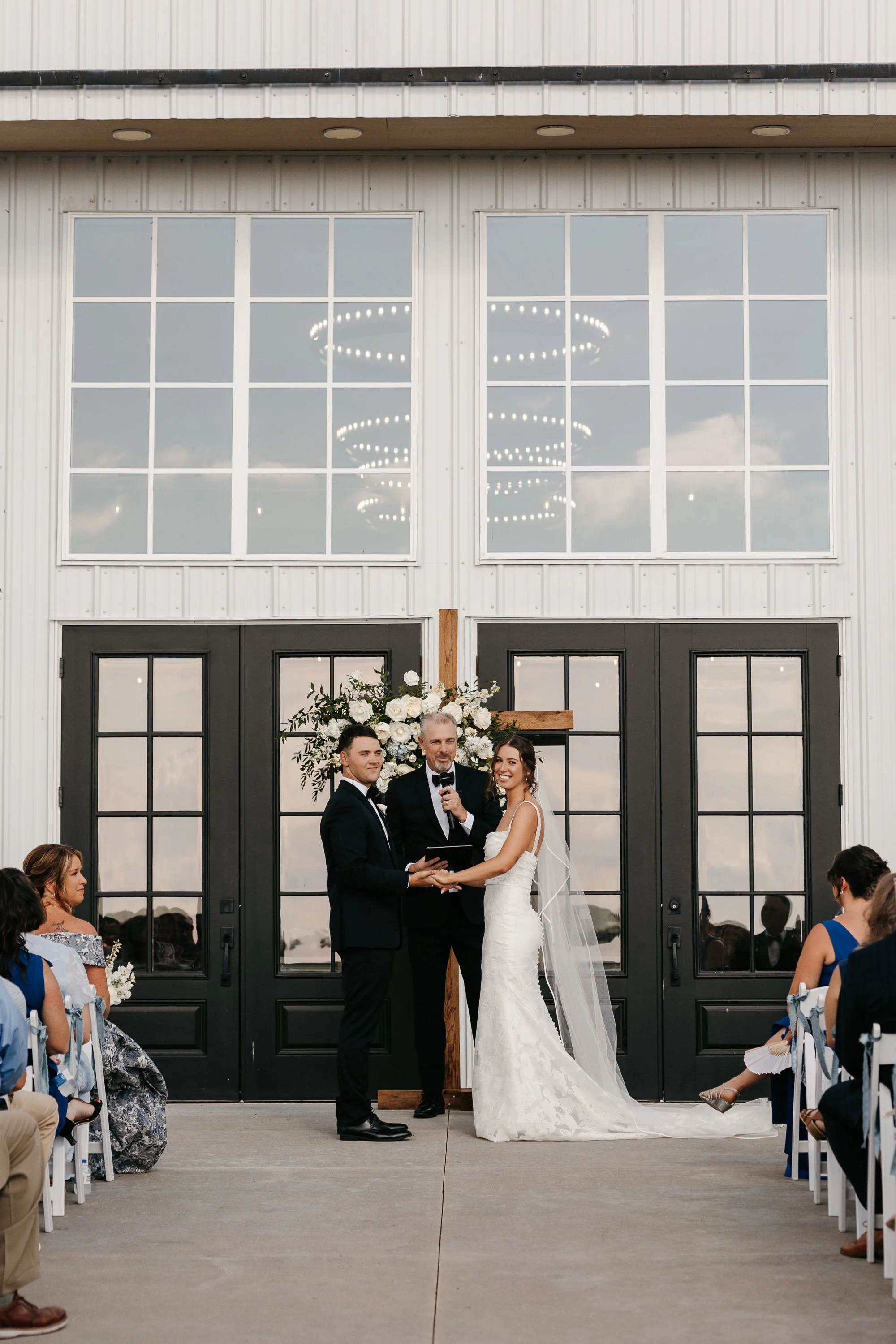wedding ceremony in front of white barn venue near wichita kansas