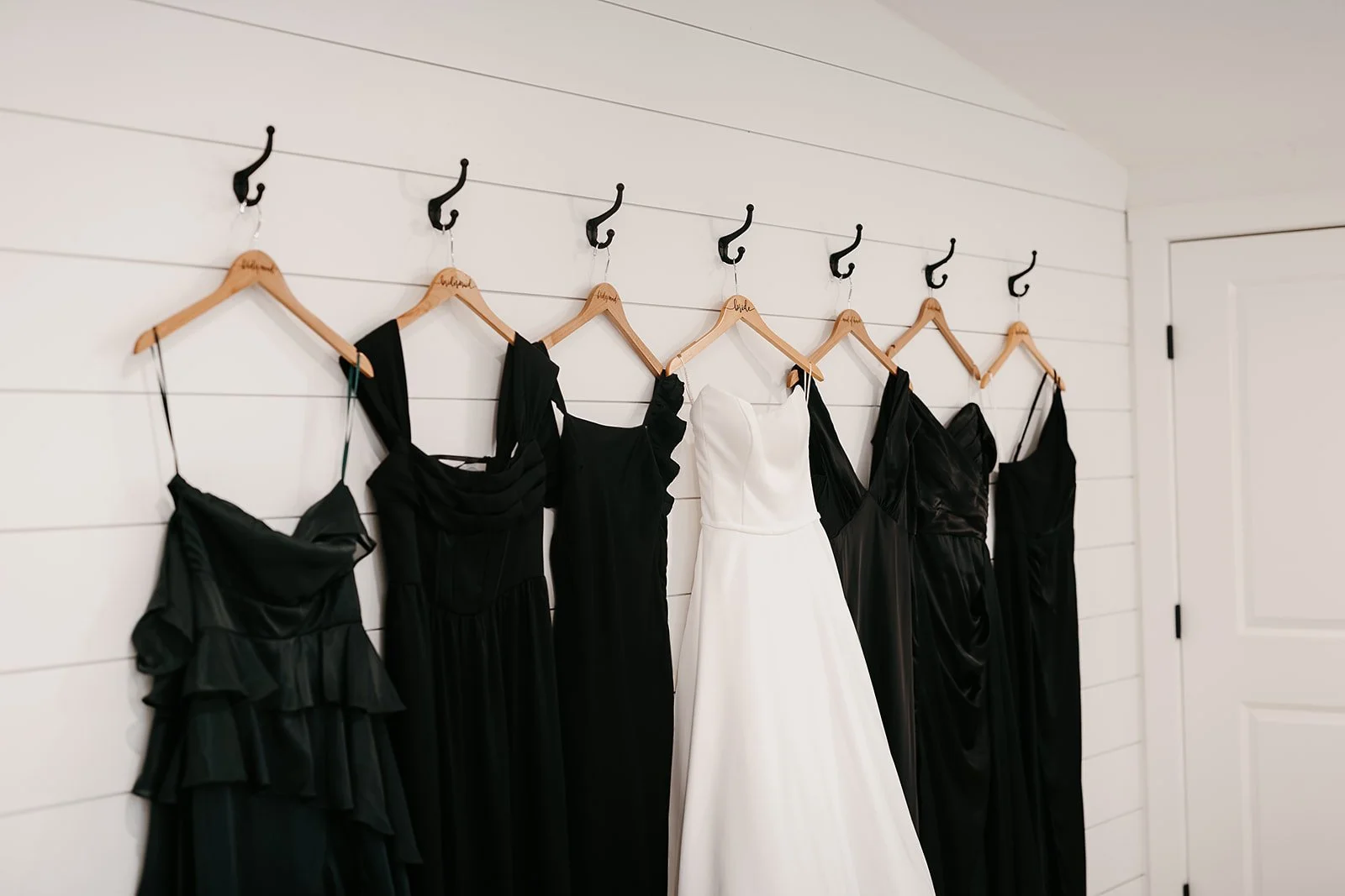 wedding dress on hooks framed by black bridesmaid dresses