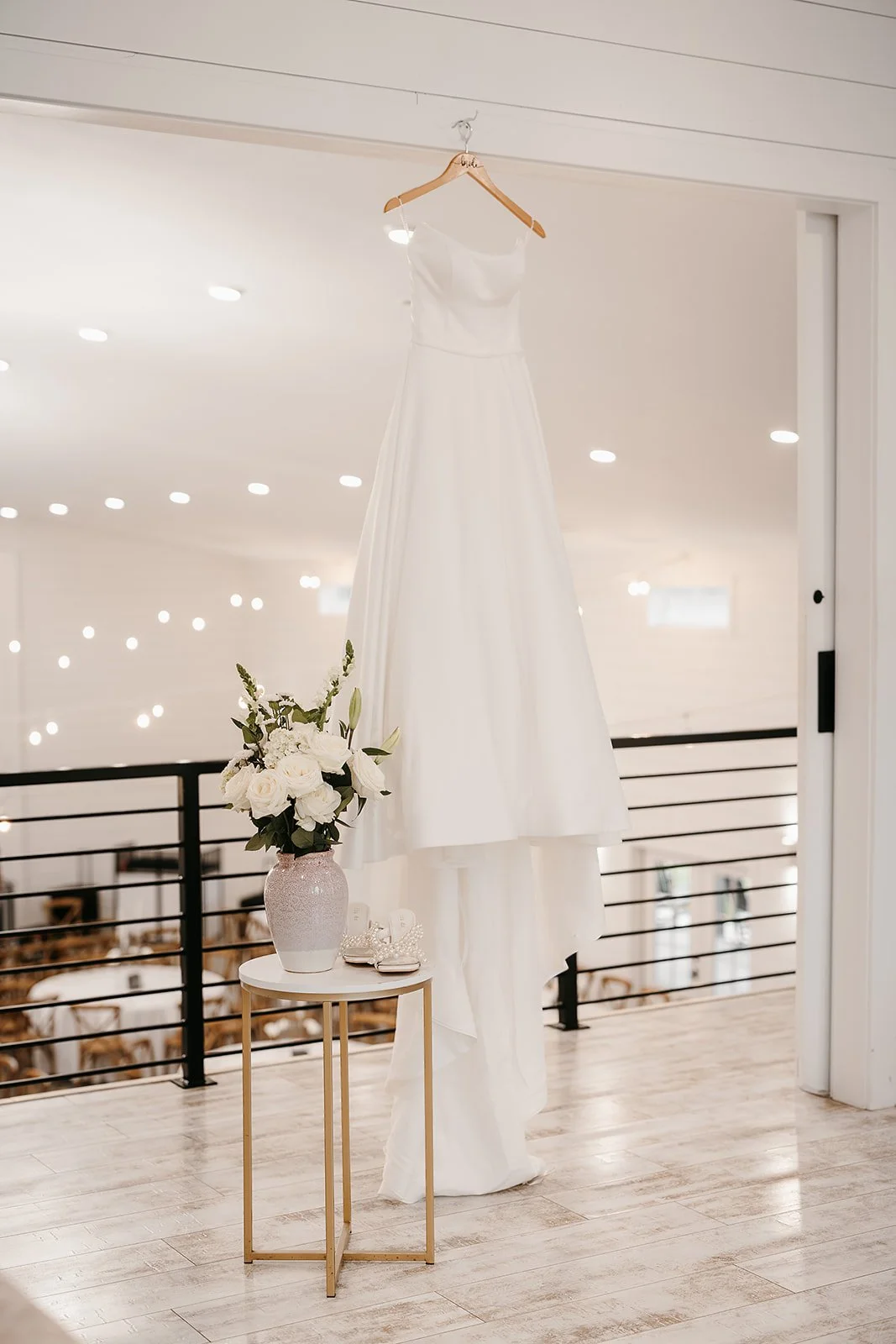 wedding dress hanging from hook overlooking the reception space